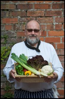 Chef at The Douglas Arms Hotel in Castle Douglas holding a basket of seasonal veg.