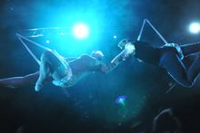 Aerial hoop artist, Elena Gatilova, and aerial chain act performer, Stephen Williams, hold hands in the air during the sneak pre