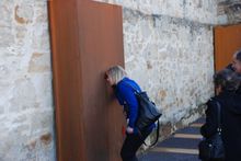 MP Rebecca White takes a look through the peephole occupying a place where there was once a door to another yard