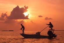 As the sun sets, a Florida Keys bonefish guide, right. points his angler to a bonefish on fly tackle off Islamorada in the  Flor