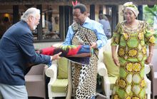 The King is handing over a gift to Mr Alan Gooderson - a rug made by locals.