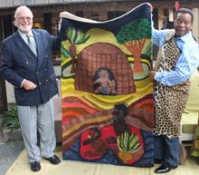 The King is handing over a gift to Mr Alan Gooderson - a rug made by locals.
