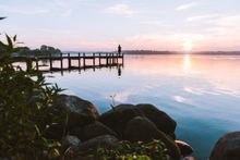 A person enjoying a sunrise on pier at Esrum Lake.