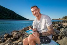 Mat Rogers signing a postcard at Tallebudgera Creek