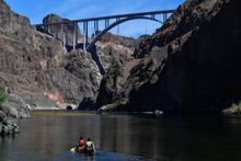 People paddle a canoe along the Colorado River below the Hoover Dam and Mike O'Callaghan–Pat Tillman Memorial Bridge