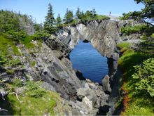 Hiker at the Berry Head sea arch, East Coast Trail, Newfoundland