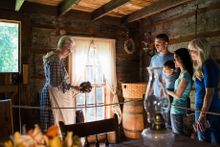 A docent shows 1800's kitchen utensils to a family touring at Historic Collinsville.