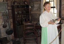 A docent shows kitchenware in the primitive pre-Civil War Lewis house.