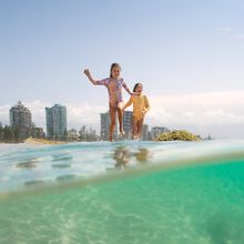 Kids running into the water at Rainbow Bay