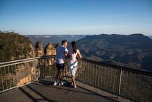 Couple enjoying views of the Three Sisters and across the Jamison Valley from Echo Point Lookout, Katoomba.