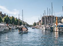 Canal running through the neighborhood Christianshavn with people sailing in a boat.