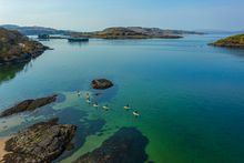 A group Stand Up Paddleboarding lesson by Basking Shark Scotland at Ganavan Bay, Oban
