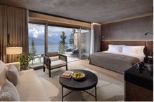 Deluxe Terrace Room with exposed timber and other natural materials, complemented by custom-made furniture and local artwork. It enjoys views to the Alpine forest and beyond.
