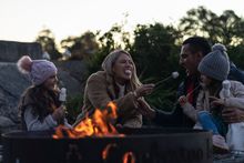 Family relaxing and roasting marshmallows at their Cockatoo Island waterfront campsite