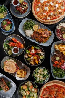 An assortment of various food dishes including pizza, salads, and grilled items.