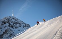 Two people skiing down a snowy slope.