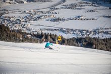 A skier whisking down the slope, looking down on the roofs of St. Johan in Tirol. 