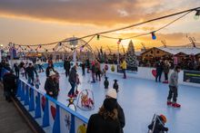 People skating on the outdoor ice rink at Christmas By The Sea at sunset.