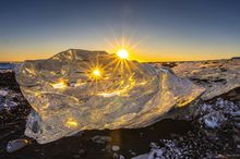 A large, clear ice crystal displayed in natural light on Diamond Beach in Iceland