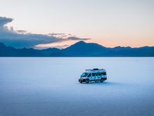 roadsurfer parked on a vast, white salt flat.