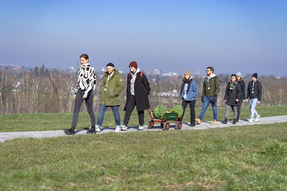 Eine Gruppe Menschen mit Bollerwagen auf Kohlfahrt / Kale tour: A group of people walking with a handcarf on a grassy path in Oldenburg.