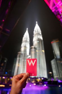 Red card with a white W logo held in front of illuminated towers.