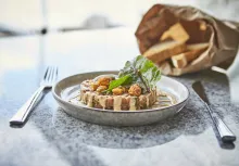 Falkensteiner Schlosshotel Velden: A bread with a spead topped with nuts and a green garnish on a plate.