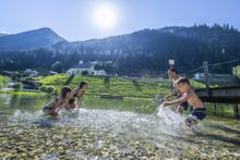 A family in a lake splashing each other with water. 