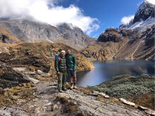 A trekker and guide pose in front of lake Om Tsho