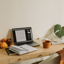 Open laptop displaying a document alongside a notebook and a coffee mug.