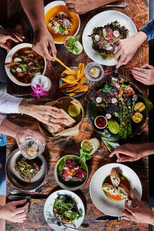 People share a tableful of food at Little Bull, a fine-dining experience in Pocho cuisine. Serving an evolving menu of taste fusions; honoring America's ever-changing influences and locally available ingredients.