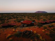 A red-roofed train travels through a desert landscape.
