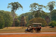 A traveler goes by a tuk-tuk, visiting the ancient city of Angkor Thom, Cambodia