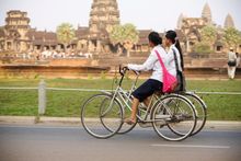 School girls riding their bikes in front of Angkor Wat Temple, Siem Reap, Cambodia