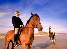 Horse riding in front of Bamburgh Castle