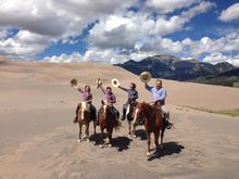 Family riding across the Great Sand Dunes National Park, Zapata Cattle & Bison Working Ranch, Colorado
