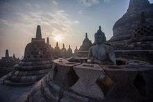 Sunrise illuminates one of the Buddha statues at the temple of Borobodur on the island of Java, Indonesia.
