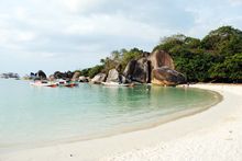 Belitung Island beach boats and swimmers at Tanjung-Tinggi