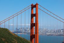 The Marin headlands afford a spectacular view of the San Francisco skyline through the red-orange superstructure of the Golden Gate Bridge.