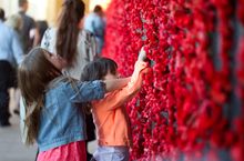 Placing a poppy on the wall at the Australian War Memorial
