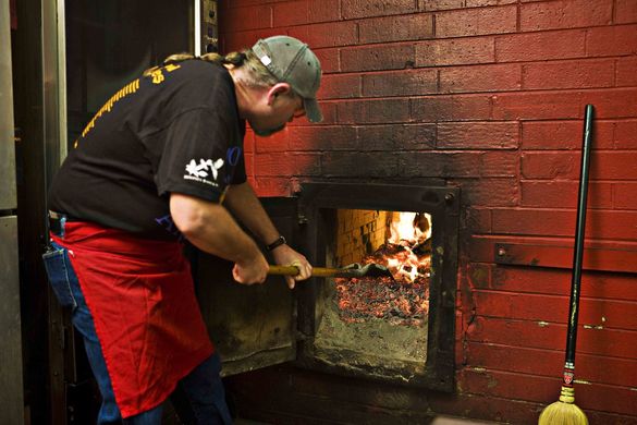 A pitmaster stokes the coals at at barbecue joint in Lexington, NC.