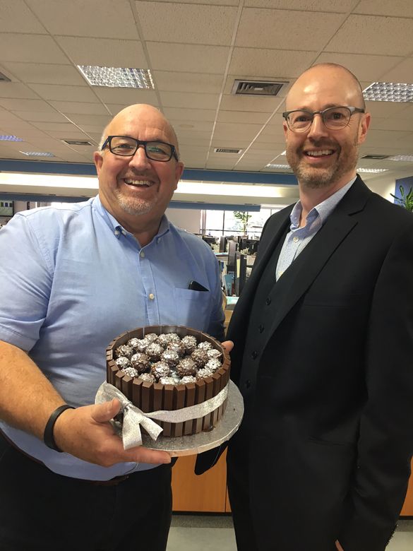 Mike Evans, Fred. Olsen’s Head of Sales (left), receives his celebratory 25th anniversary cake from Justin Stanton, Sales and Marketing Director, at Fred. Olsen House in Ipswich, Suffolk 