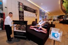 Executive Chef Darren Ong spins the hand wheel to light up the life-sized recycled materials race car, Royal Plaza on Scotts