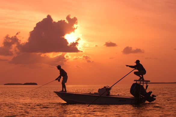 As the sun sets, a Florida Keys bonefish guide, right. points his angler to a bonefish on fly tackle off Islamorada in the  Flor
