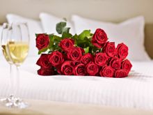 Roses and champagne on bed