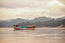 A local boat cruises along the Mekong River in Laos