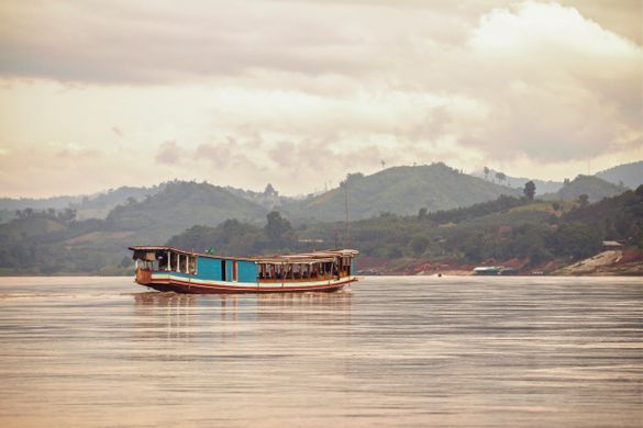 A local boat cruises along the Mekong River in Laos A local boat cruises along the Mekong River in Laos