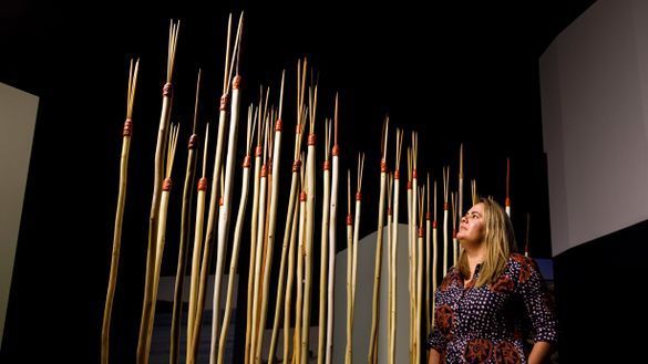 Curator Shona Coyne with fishing spears made by the Dharawal community, similar to three in the exhibition taken by Captain Cook in 1770.