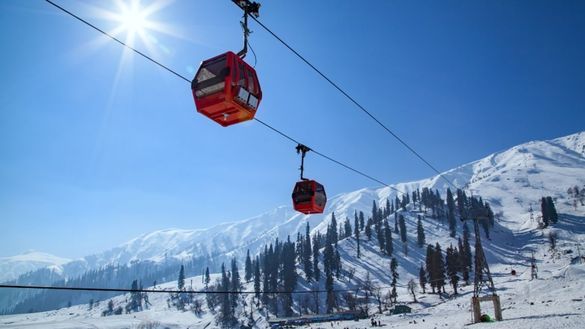 Photo of a red cable car travelling through the mountains in Gulmarg, Kashmir