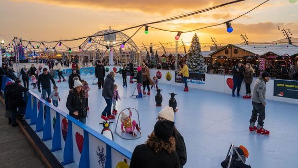 People skating on the outdoor ice rink at Christmas By The Sea at sunset.